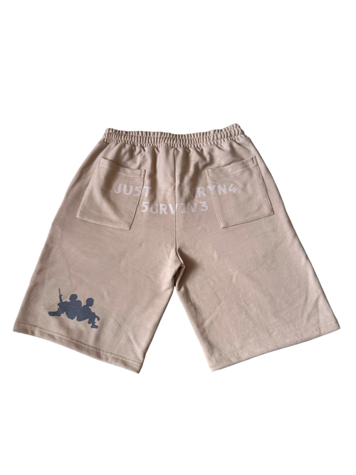 A pair of beige drawstring shorts with a gray graphic of two soldiers on the lower left leg and white text on the back pocket reading 'JUST SORTING & SURVIVES'.